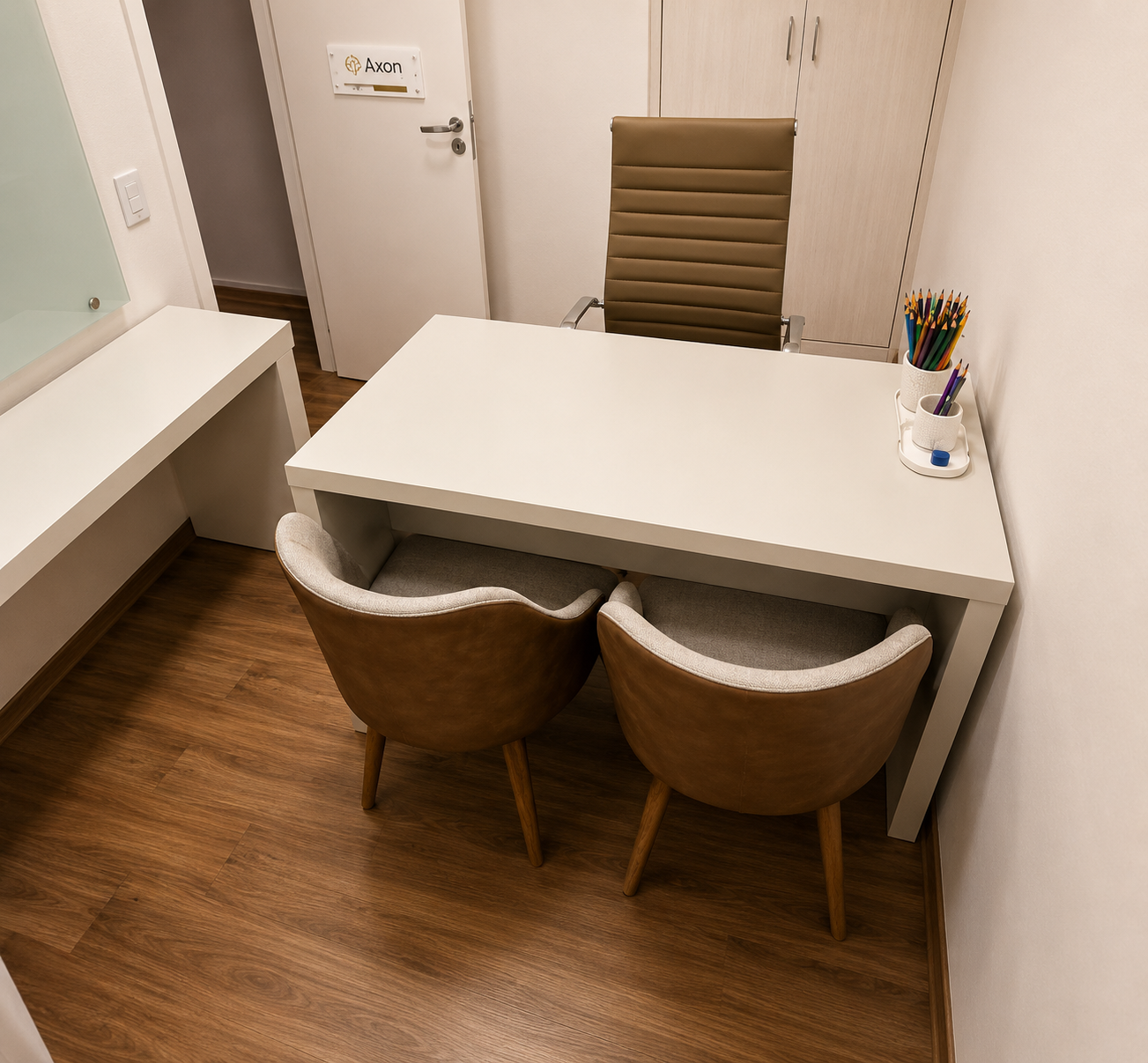 Consultório 01 do Instituto Axon Savant com mesa, cadeiras e identificação na porta.